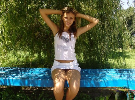 Teen amateur crosses and uncrosses her legs on an outdoor bench in a miniskirt 73739774